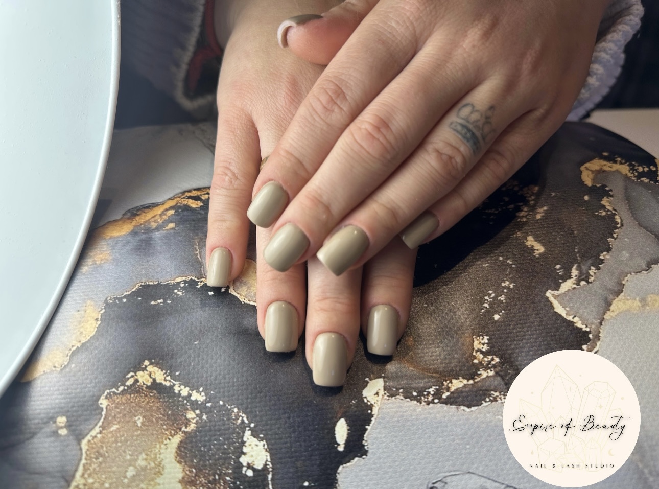 Matte taupe nagels op donker marmer met gouden aders